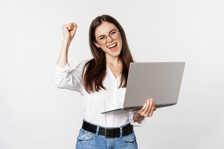enthusiastic-office-woman-businesswoman-holding-laptop-and-shouting-with-joy-celebrating-and-rejoicing-standing-over-white-background-min